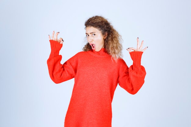 vrouw in rood sweatshirt dat plezierteken toont.