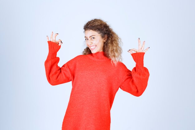 vrouw in rood sweatshirt dat plezierteken toont.