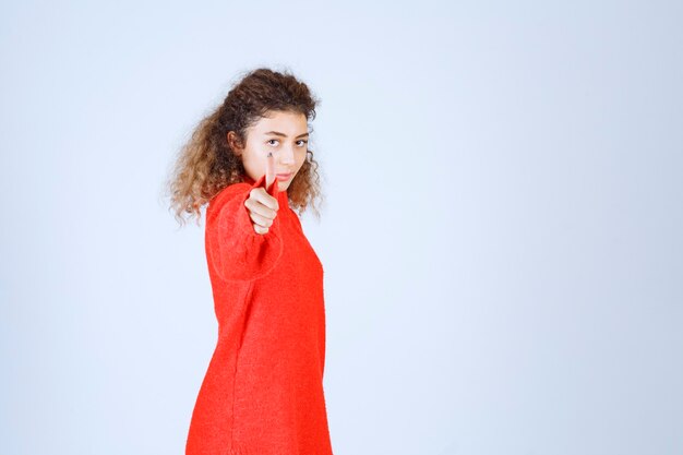 Vrouw in rood sweatshirt dat plezierteken toont.