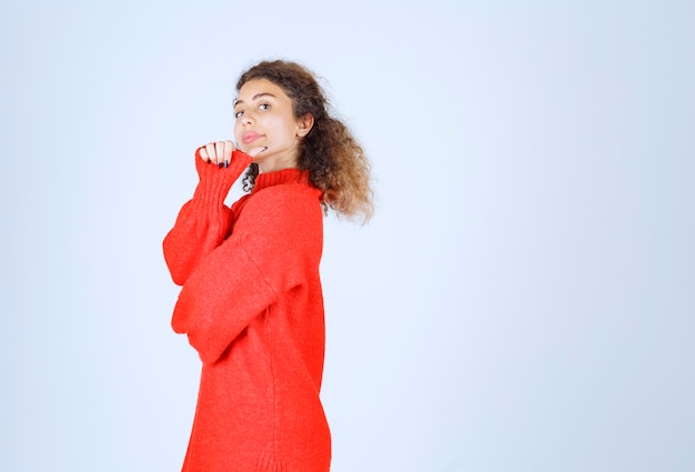 vrouw in rood sweatshirt die glimlachende en verleidelijke poses geeft.