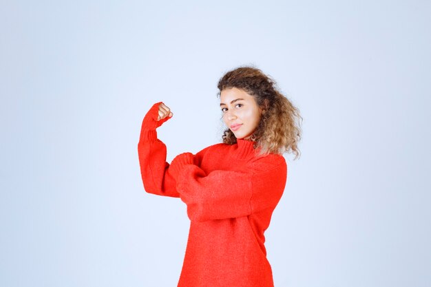 vrouw in rood sweatshirt die haar vuist toont en haar macht bedoelt.