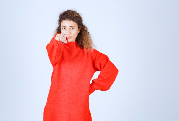 vrouw in rood sweatshirt die haar vuist toont en haar macht bedoelt.