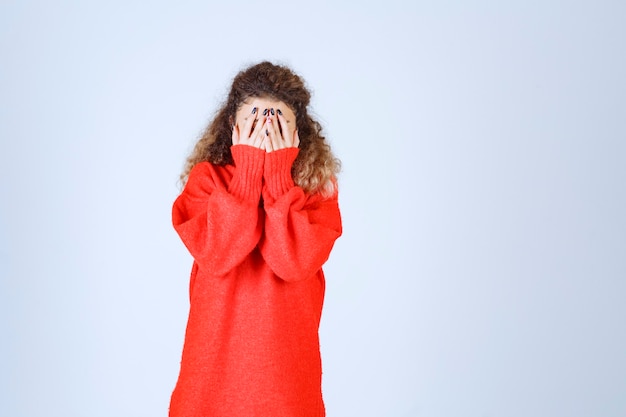 Vrouw in rood sweatshirt die over haar vingers kijkt.