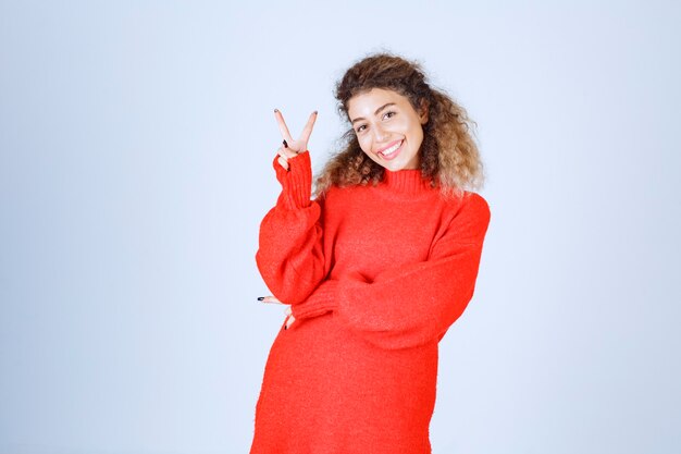 vrouw in rood sweatshirt die vrede en plezierteken tonen.