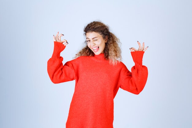 vrouw in rood sweatshirt die vrede en plezierteken tonen.