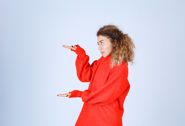 Vrouw in rood sweatshirt met de geschatte hoeveelheid of grootte van een product.