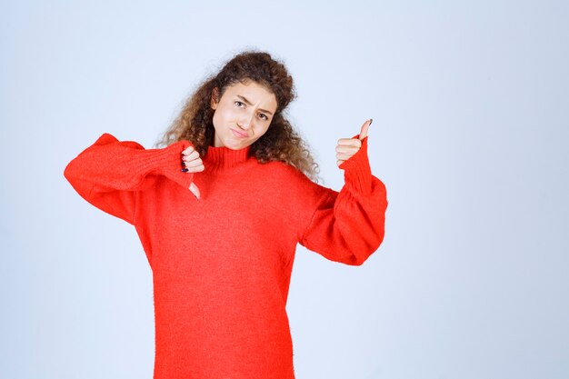 vrouw in rood sweatshirt met duim op en neer tekenen.