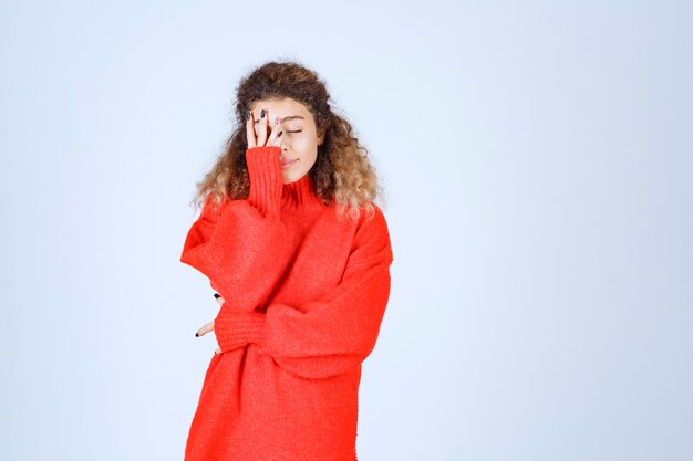 vrouw in rood sweatshirt ziet er moe en slaperig uit.