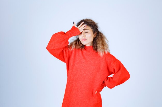 vrouw in rood sweatshirt ziet er slaperig uit.