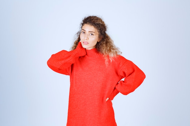 vrouw in rood sweatshirt ziet er verward en attent uit.