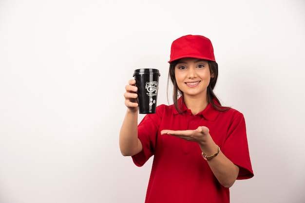 Vrouw in rood uniform met een kopje koffie op een witte achtergrond.