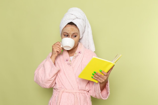 vrouw in roze badjas koffie drinken en boek lezen
