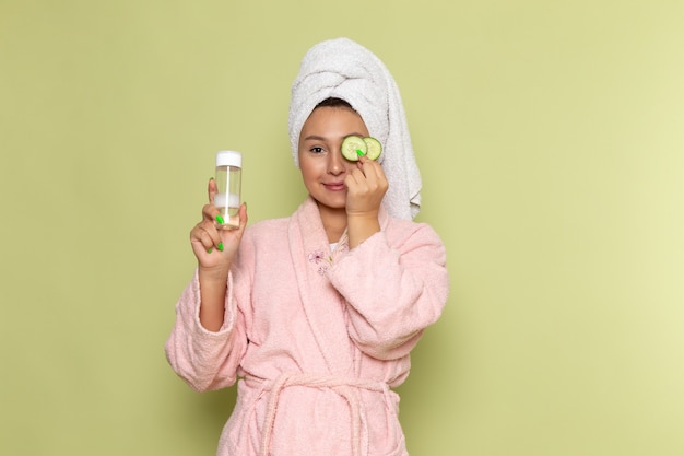 vrouw in roze badjas met spray kolf en komkommer ringen