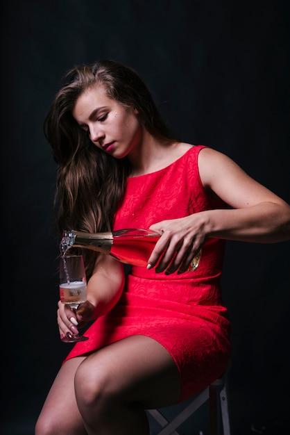 Vrouw in roze gieten champagne in glas