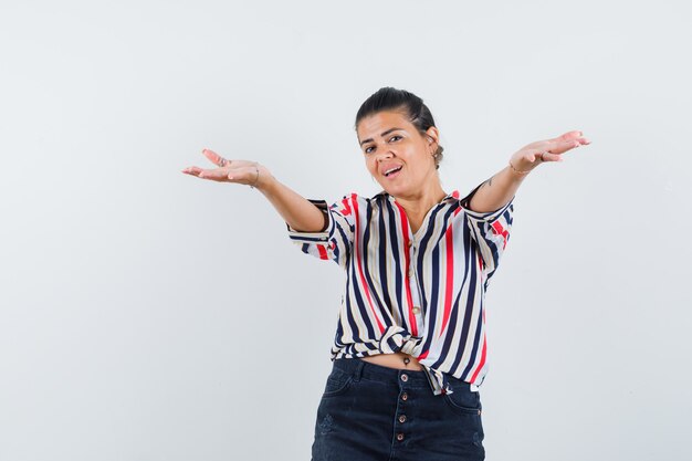 vrouw in shirt, rok die armen opent voor knuffel en er vrolijk uitziet