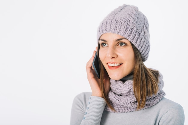 Vrouw in sjaal en hoed die op telefoon spreekt