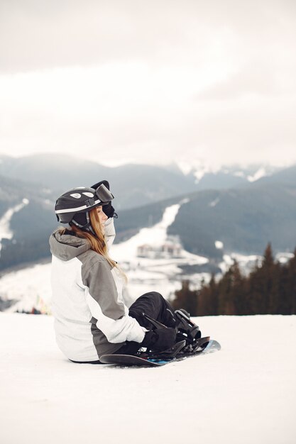 Vrouw in snowboardkostuum. Sportvrouw op een berg met een snowboard in de handen aan de horizon. Concept over sport