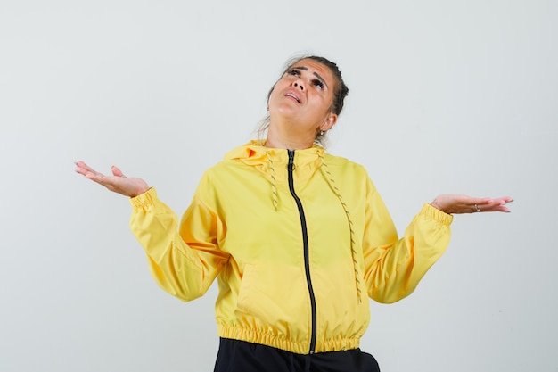 Vrouw in sport pak schalen gebaar maken terwijl opzoeken en op zoek verward, vooraanzicht.