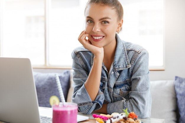 Vrouw in stijlvolle denim jasje in coffeeshop