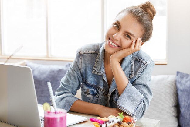 Vrouw in stijlvolle denim jasje in coffeeshop