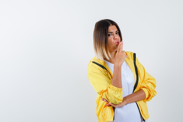 Vrouw in t-shirt, jasje met pistoolgebaar en op zoek naar zelfverzekerd, vooraanzicht.