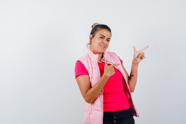 Vrouw in t-shirt, vest met geweergebaar en vrolijk kijkend