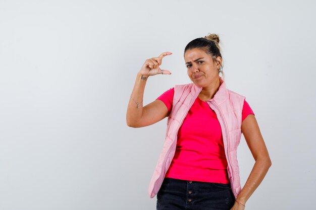 Vrouw in t-shirt, vest met klein bordje en aarzelend