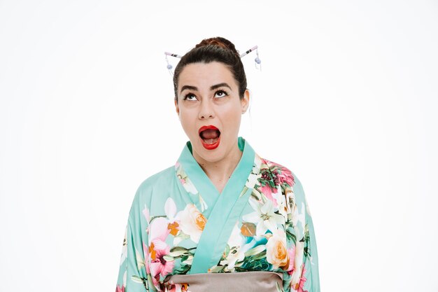 Vrouw in traditionele Japanse kimono kijkt geïrriteerd en geïrriteerd op op wit