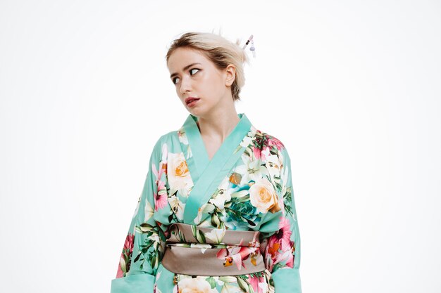 Vrouw in traditionele Japanse kimono kijkt opzij en is geïrriteerd en geïrriteerd met rollende ogen op wit