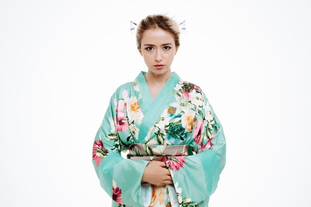 Vrouw in traditionele Japanse kimono met serieuze zelfverzekerde uitdrukking op wit