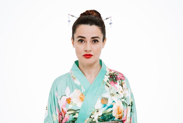 Vrouw in traditionele Japanse kimono met serieuze zelfverzekerde uitdrukking op wit
