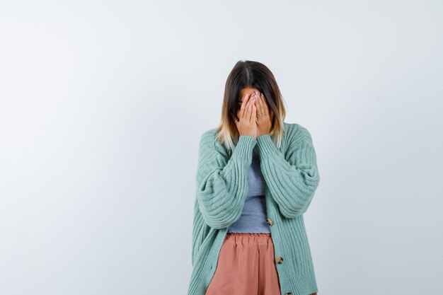 Vrouw in vrijetijdskleding die handen op gezicht houdt en depressief, vooraanzicht kijkt.