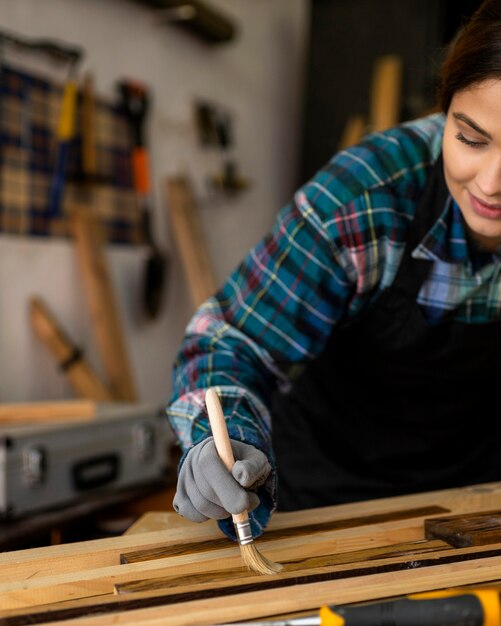 Vrouw in werkplaats stof van houten planken borstelen