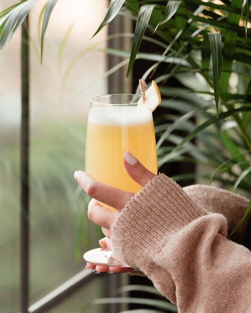 Vrouw in winter shirt met een glas ananas sap bij het raam.