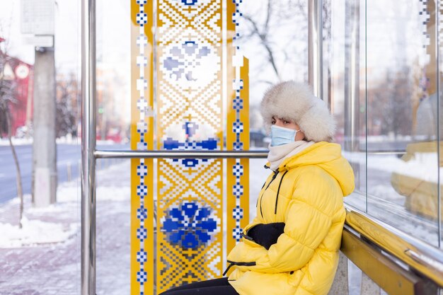 Vrouw in winterkleren op een koude dag te wachten op een bus bij een bushalte