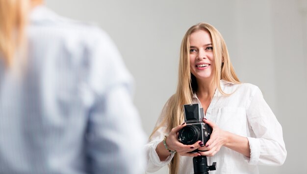 Vrouw in wit overhemd die haar camera met behulp van