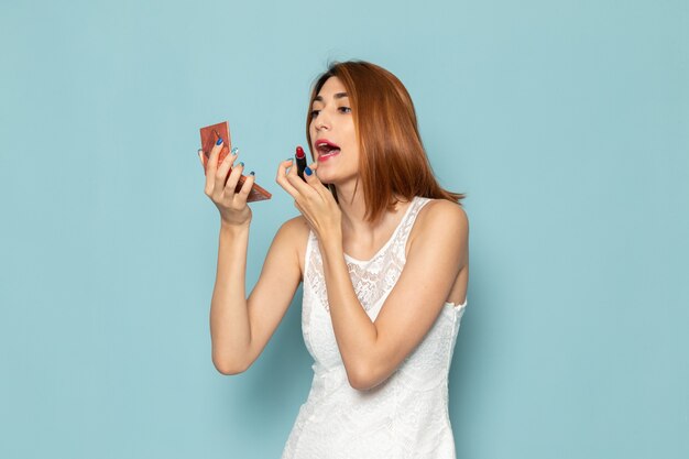 vrouw in witte blouse en blauwe spijkerbroek make-up doen