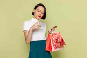 Gratis foto vrouw in witte blouse en groene rok met winkelen pakketten en telefoon vrouwelijke kleren mannequin