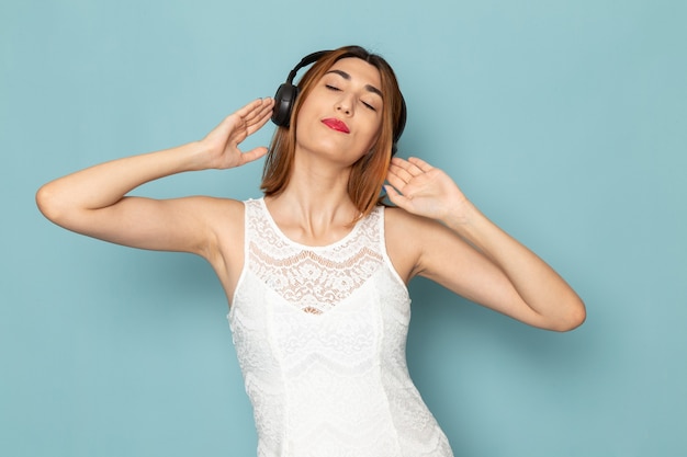 Vrouw in witte blouse en spijkerbroek luisteren naar muziek