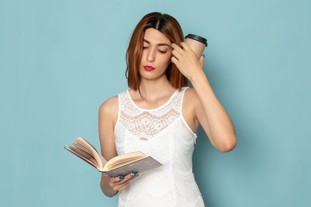 vrouw in witte blouse en spijkerbroek met koffiekopje en boek