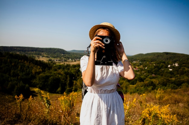 Vrouw in witte kleding die een foto van camera neemt