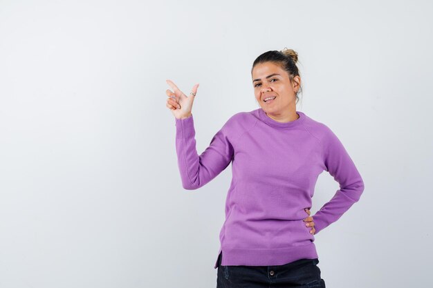 Vrouw in wollen blouse die naar boven wijst en er zelfverzekerd uitziet