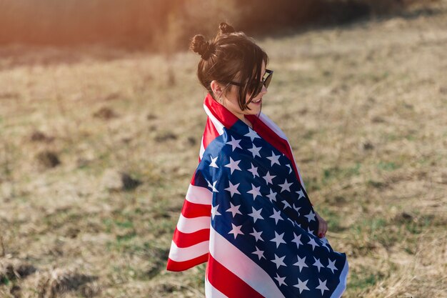 Vrouw in zonnebril in Amerikaanse vlag wordt verpakt die
