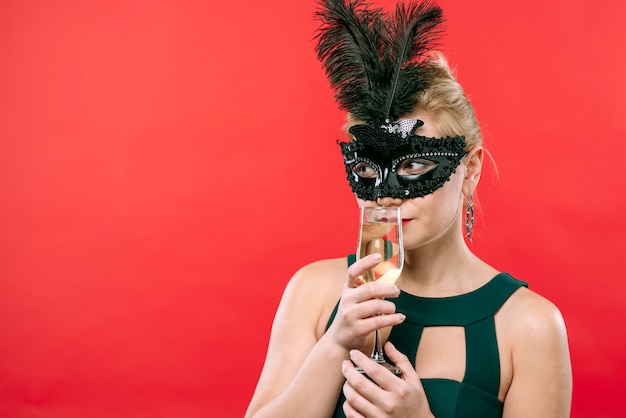 Vrouw in zwart masker met champagneglas