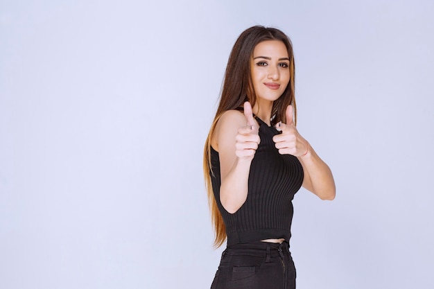 Vrouw in zwart shirt met duim omhoog teken.