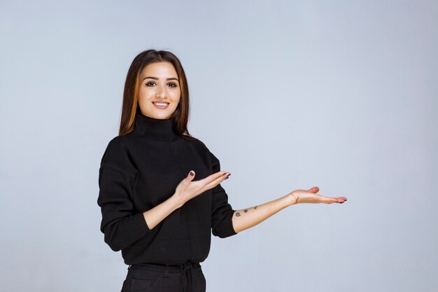 vrouw in zwart shirt wijst iets aan de rechterkant.