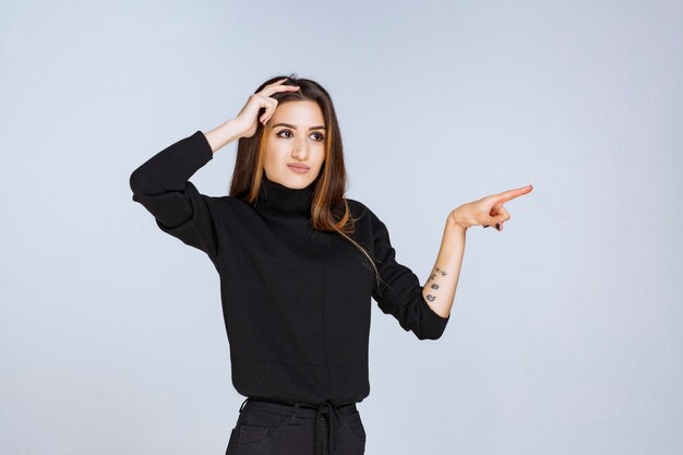 vrouw in zwart shirt wijst iets aan de rechterkant.