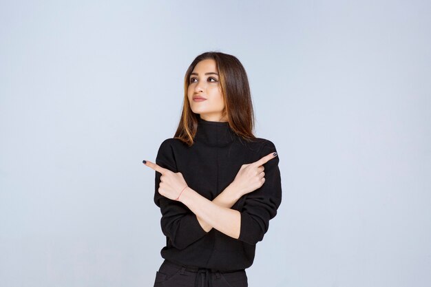 vrouw in zwart shirt wijst iets hierboven.