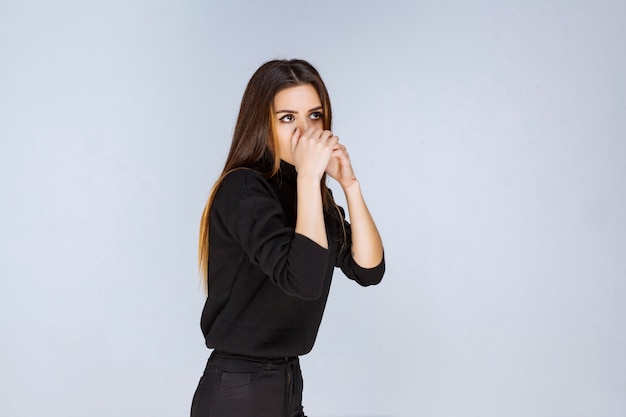 Vrouw in zwart shirt ziet er verward en attent uit.