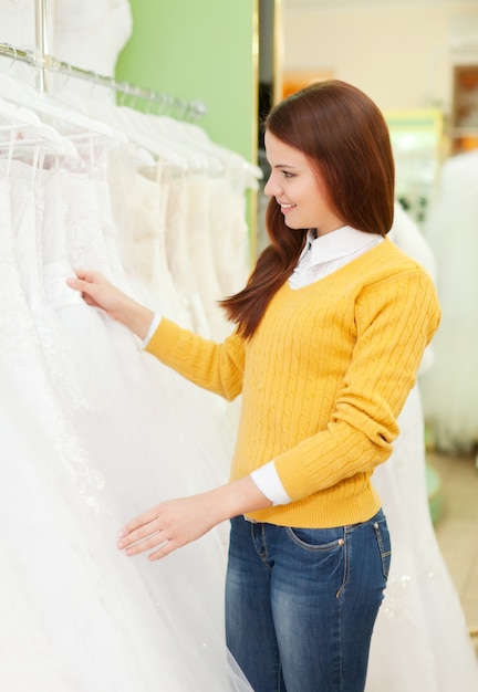 vrouw kiest jurk in de winkel van de bruiloft mode